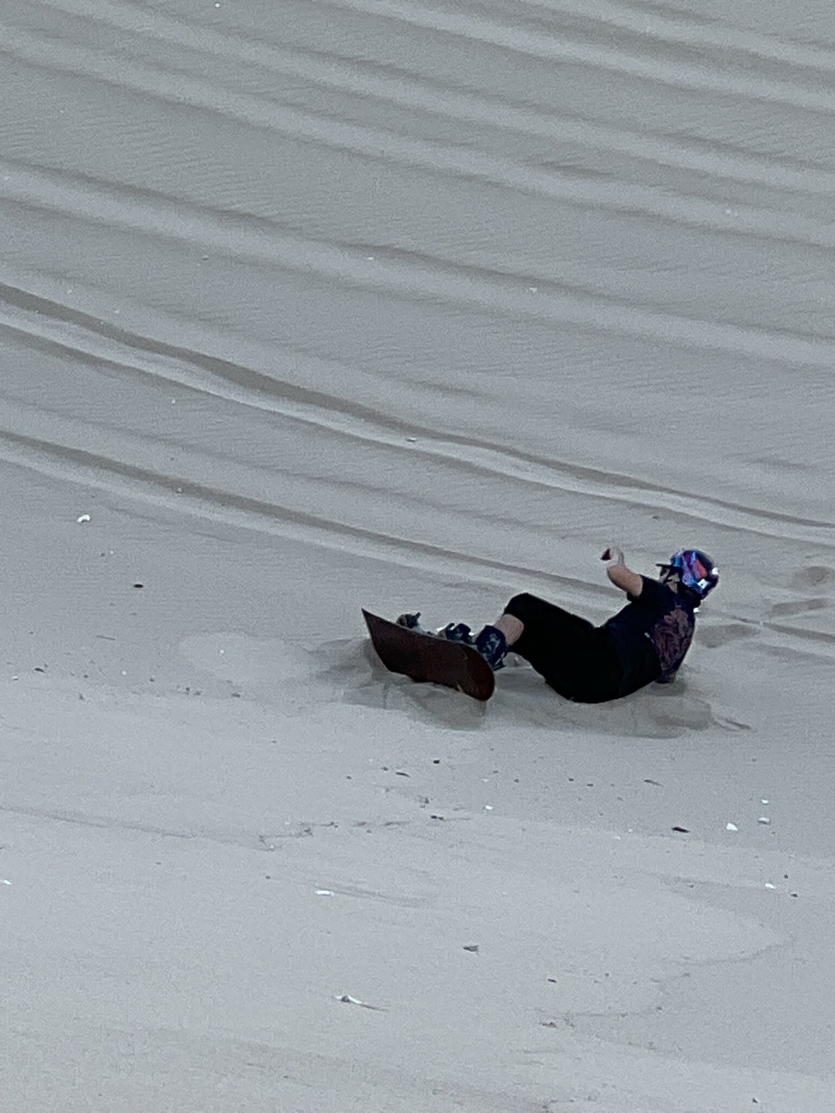 Martín cayéndose del sandboard en la arena, en Huacachina.